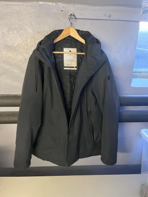 Blågrå dunjacka från Revolution - Säljer en blågrå parkas från Revolution i storlek Large. Jackan har huva, dragkedja framtill och flera praktiska fickor. Insidan är quiltad för extra värme och komfort. Perfekt för kalla dagar och har en stilren, minimalistisk look.