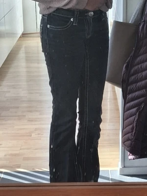 Svarta bootcut jeans med sömmar på fickorna - Hejjj jag säljer ett par svarta bootcut jeans med vita sömmar på bakfickorna. Jeansen har låg midja och klassisk femficksmodell. Det är spegeln som är smutsig inte byxorna!