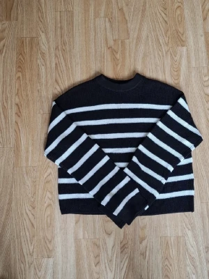 Svartvit randig stickad tröja H&M - Stickad tröja från H&M i svart med vita horisontella ränder. Tröjan har rund halsringning och långa ärmar. Perfekt för dig som gillar klassiska ränder och en avslappnad stil.