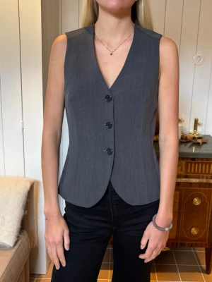 Grå kostymväst med knappar - Snygg grå kostymväst med tre svarta knappar framtill och figurnära passform. Den är ifrån Hm i storlek S🌸aldrig använd 