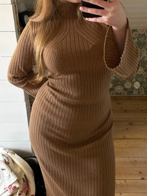 Beige/brun ribbad klänning - Super fin ribbad klänning. Går bode att klä upp och klä ned. Är figur nära och stetchig och väldigt bekväm. Nästan oandvänd. Den är lite högte i halsen och har utsvängda armar. Pris går att diskuteras.