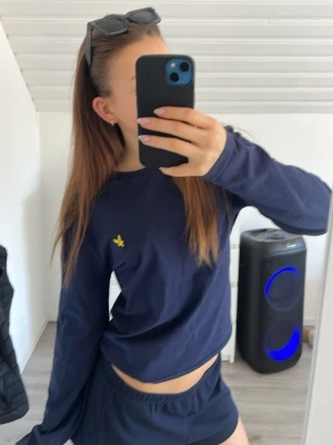 Marinblå långärmad topp från Lyle & Scott - Snygg marinblå långärmad topp från Lyle & Scott med den klassiska gula loggan broderad på bröstet. Tillverkad i mjuk bomull och har en normal passform. Perfekt till jeans eller shorts för en clean och enkel look. Tröjan är i Storlek M men passar perfekt på mig som har storlek S. Den har använts två gånger och är då u superfint skick. Original priset ligger runt 500kr men jag säljer den för lite billigare då jag vill bli av med den 💗