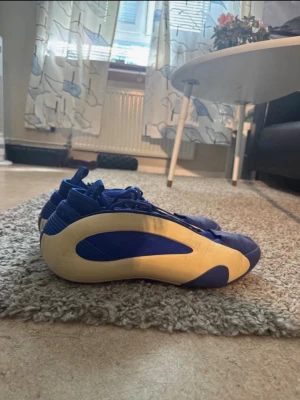 Adidas HARDEN VOL 8 blå  - Säljer ett par unika Adidas sneakers i blått och beige med retroinspirerad design. Skorna har en låg siluett, rundad tå och tydliga Adidas-ränder bak. Ovandelen är i textil och syntet, och sulan är i gummi. Perfekta för dig som gillar sportig och stilren look.
