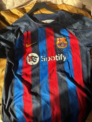Gul FC Barcelona matchtröja Nike - Snygg gul FC Barcelona matchtröja från Nike med Spotify-logga på bröstet och klubbmärke. Tröjan har korta ärmar och rund hals, samt diskreta ränder i klubbens färger på ärmsluten. Perfekt för dig som älskar fotboll och vill representera Barca.