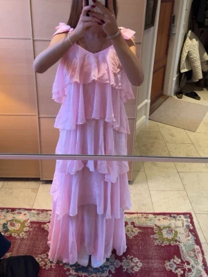 Ljusrosa volangklänning - Jättefin ljusrosa långklänning med volanger samt justerbara rosetter i axlarna. Köpt från Vero Moda i storlek xs. Helt oanvänd med lappen kvar!💗Nypris 1200kr