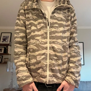 Camomönstrad vindjacka från Woolrich - Windbreaker från Woolrich. Färg camo grön samt storlek M. Skick 8/10 lite smutsig och finns smått tecken på användning men annars inga problem. Om du har frågor eller funderingar så kom dm.👍