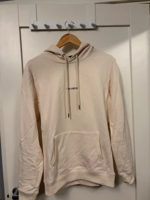 Beige hoodie från Les Deux - Säljer en stilren beige hoodie från Les Deux med broderad logga på bröstet. Hoodien har känguruficka, justerbar huva med snörning och långa ärmar. Perfekt för en avslappnad och trendig look.🤩🙌