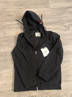 Moncler Windbreaker - Snygg svart vindjacka från Moncler med huva och dragkedja framtill. 9/10 skick använd 1-2 gånger. Skicka PM!