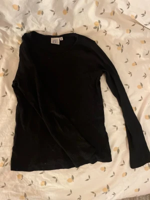 Svart långärmad tröja från sweet heart barn st 122/128 - En enkel svart långärmad tröja från sweet heart med rund halsringning. Tröjan är i ett mjukt och tunt material, perfekt att ha som basplagg eller under en jacka. Passar till det mesta och är lätt att matcha. Barn storlek 122/128