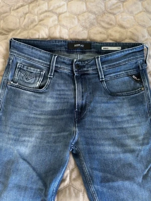  Replay jeans  - Snygga blå slim fit jeans från Replay med klassisk femficksmodell och diskreta slitningar framtill. Jeansen har normal midja och raka ben, tillverkade i mjuk denim med stretch för extra komfort. Perfekta för en avslappnad och trendig look.