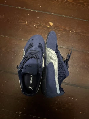 Marinblå Puma sneakers med mesh - Snygga marinblå sneakers från Puma med silverfärgade detaljer på sidan. Skorna har en kombination av mocka och mesh för extra andningsförmåga och komfort. Klassisk snörning och Ortholite-innersula för skön känsla hela dagen.