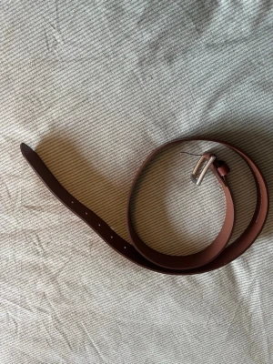 läderbälte H&M - Snyggt brunt skärp från H&M i äkta skinn med klassiskt silverfärgat spänne. Perfekt för att lyfta vilken outfit som helst och funkar till både jeans och kostymbyxor. Enkel och stilren design som passar till det mesta.