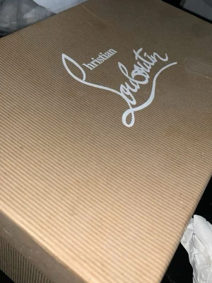 Svarta sneakers från Christian Louboutin - Snygga svarta sneakers från Christian Louboutin med klassisk röd sula och diskret logga. Skorna har en låg profil, snörning och är tillverkade i ett lyxigt material som ger en exklusiv känsla. Perfekta för dig som vill sticka ut med stil.