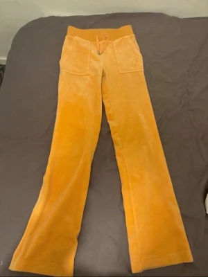 Orangea juicy byxor - Ett par orangea juicy byxor som har tappat ens ”knappen” på ena bandet men annars väldigt fina och i bra skick annars 