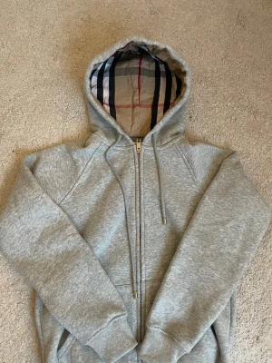 Grå hoodie med dragkedja Burberry - Helt nytt skick, känns som xs. Jättebra kvalitet och passar till det mesta!✨