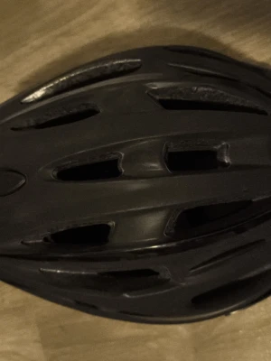Svart cykelhjälm med ventilationshål - Säljer en svart cykelhjälm med flera ventilationshål och aerodynamisk design. Hjälmen är tillverkad i lätt plastmaterial och har en modern, sportig look som passar för både stadscykling och träning.
