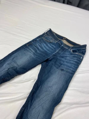 Jack & Jones jeans - Snygga mörkblå slim fit jeans med slitningar och tvättade detaljer. Klassisk femficksmodell med knapp och dragkedja framtill. Jeansen har kontrastsömmar och är tillverkade i denim med lätt stretch för skön passform.