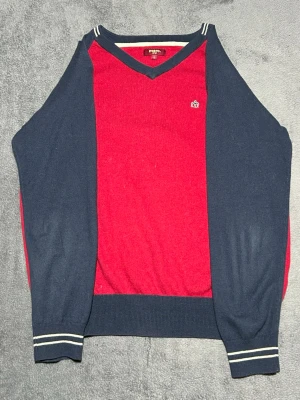 Merc London V-Neck Sweater – Red/Navy – Size L - Stickad tröja från Merc London i röd och navy färgkombination.  Klassisk V-neck modell med liten broderad Merc-logga på bröstet.  En stilren tröja som passar bra till både jeans och chinos.  Detaljer • Merc London • Stickad tröja • V-neck • Röd / navy • Storlek L  📦 Skickas snabbt 💬 Hör av dig vid frågor