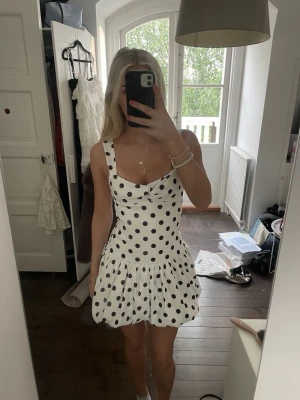 Vit prickig kort klänning🤍🖤 - Supersöt vit klänning med svarta prickar och breda axelband. Klänningen har en ballong kjol och en snygg v-ringad urringning. Materialet känns mjukt och svalt, perfekt för varma dagar. Finns ingen storlek men passar M eller stor S🌟Modellen är kort. 