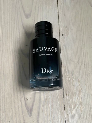 Dior Sauvage Eau de Parfum - Dior Sauvage Eau de Parfum i en elegant mörkblå glasflaska med svart lock och tydlig logotyp. Doften är modern och maskulin, perfekt för dig som vill sticka ut med en fräsch och kryddig parfym. Flaskan har en stilren och lyxig design. Köpt på blau perfemerias i barcelona i somras. Ca 75-80% full 60 ml flaska. Box kommer med. Bara att fråga om du undrar något