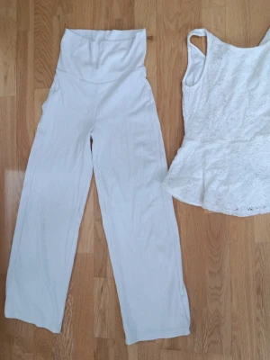 Vit set med line och byxor Kappahl och H&M storlek 134/140 - Säljer ett vitt linne med peplum och breda axelband. Toppen är täckt av vacker spets och har en lätt utsvängd nederdel som ger en feminin siluett. Perfekt att styla med jeans eller kjol för en fräsch look.