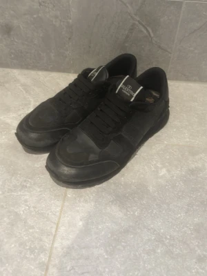 Valentino rockrunners  - Snygga helsvarta sneakers från Valentino med klassisk låg profil. Skorna har svarta skosnören, diskret logga på plösen och är tillverkade i en mix av läder och textil. Perfekta för dig som gillar stilrena och exklusiva sneakers. Pris kan diskuteras 