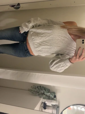 Ljusgrå offshoulder sweatshirt - Ljusgrå sweatshirt med offshoulder-design och bred mudd i midjan. Tröjan har långa ärmar och är tillverkad i mjukt bomullsmaterial. Perfekt för en avslappnad och trendig look.