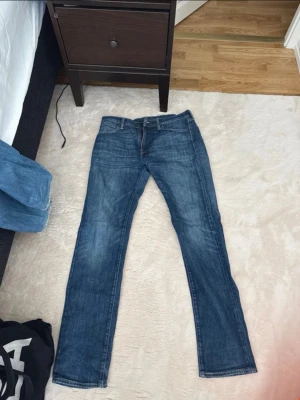 Blå Levi's  jeans - Säljer ett par klassiska blå Levi's jeans med bootcut passform. Jeansen har fem fickor, knappgylf och den ikoniska läderlappen bak i midjan. Tillverkade i slitstark denim som ger en tidlös look. Perfekta för dig som gillar en avslappnad men snygg stil.