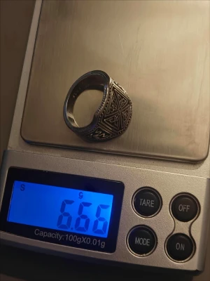 Antik silverring S 925 med mönster storlek 8 - Säljer en robust ring i 925 silver vikt 6.66g  med detaljerade, antikinspirerade mönster på sidorna. Ringen har en fyrkantig front med inristade ornament och små prickdetaljer längs kanterna. Perfekt för dig som gillar unika accessoarer med vintagekänsla.