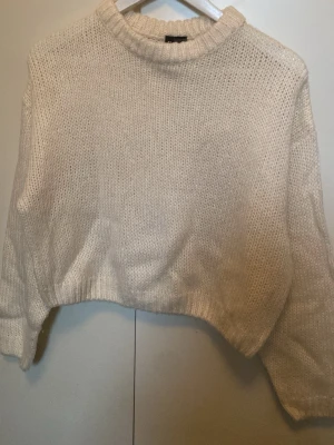 Benvit cropped stickad tröja - Säljer en benvit cropped stickad tröja med rund hals och långa ärmar. Tröjan har en lite oversized passform och är gjord i ett mjukt, tjockt garn.