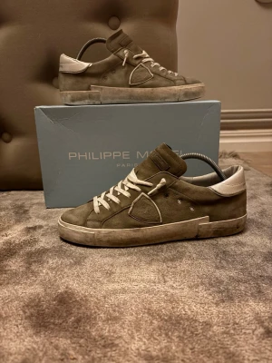 Philippe Model grå sneakers i mocka - Snygga sneakers från Philippe Model i grå mocka med vita detaljer och vit sula. Skorna har lågt skaft, vita skosnören och en ikonisk sköldlogga på sidan. Perfekta för dig som gillar stilrena och trendiga sneakers med en exklusiv känsla. Knappt använda kvitto finns kontakta för frågor och funderingar 