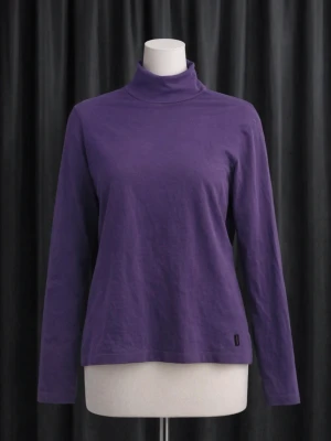 Lila polotröja med lång ärm - En stilren lila polotröja med lång ärm och rak passform. Tillverkad i mjukt material som känns skönt mot huden. Perfekt för lager på lager och enkel att matcha med olika outfits.