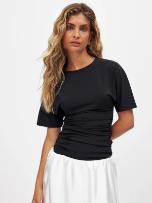 Svart  topp med rynkade detaljer - Svart topp med korta ärmar och rund halsringning. Toppen har en croppad passform och rynkade detaljer längs sidorna som ger en snygg siluett. Perfekt att styla med både kjol och jeans för en trendig look.