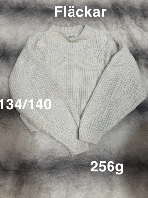 Vit stickad tröja barn 134/140 - Klassisk vit stickad tröja i grovstickat material med rund hals och ribbade muddar. Tröjan har en avslappnad passform och är perfekt för kyligare dagar. 🌸 Två fläckar. Storlek 134/140