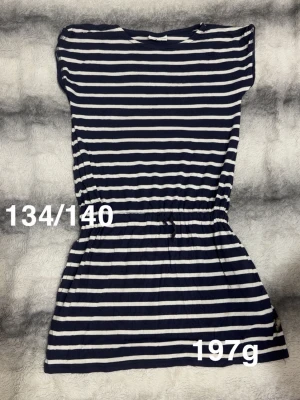 Marinblå och vit randig klänning - Snygg marinblå och vit randig klänning med kort ärm och resår i midjan. Klänningen har en avslappnad passform och är perfekt för varma dagar. 🌸 Fint använt skick. Storlek 134/140 