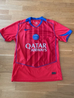 PSG röd matchtröja Barcola 29 - Röd Paris Saint-Germain matchtröja från Nike med blå detaljer och klubbmärke på bröstet. Qatar Airways-logga framtill och B. Barcola 29 tryckt på ryggen. Perfekt för fotbollsfans som vill sticka ut på planen eller läktaren. Trycket på tröjan har skrynklats lite men självaste tröjan har inga brister. Kontakta gärna vid frågor.