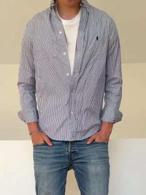 Ljusblå Randig Ralph Lauren Skjorta  - Randig Ralph Lauren skjorta i barnstorlek 18-20 vilket motsvarar herrstorlek S! Bra skick och Hör gärna av er vid frågor elr funderingar!!