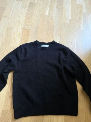 Svart stickad tröja från Kappahl - En svart stickad tröja från Kappahl med rund halsringning och ribbade muddar vid ärmslut och nederkant. Enkel och stilren design som passar perfekt till många olika outfits.