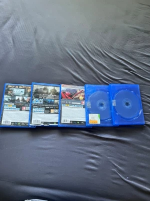 PS4 spel: Battlefield & Call of Duty - Samling med fem PS4-spel: Battlefield 1, Battlefield 4 och Call of Duty Ghosts, Minecraft och GTA 5. Alla i blå plastfodral med klassisk PS4-design. Perfekt för dig som gillar action och förstapersonsskjutare. Spelen är märkta med 18+ PEGI. Själva boxarna är i lite dåligare skick fast skivorna är helt perfekt och funkar jätte bra