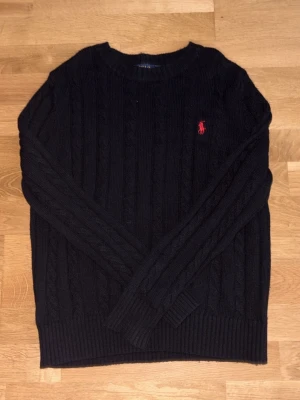Ralph Lauren Cableknit - Svart stickad cableknit från Polo Ralph Lauren i storlek S. Väldigt bra skick och har mycket kvar att ge. Hör av dig vid minsta fundering!