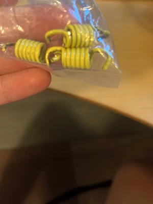 Kopplingsfjädrar gul - Säljer ett set med små gula metallfjädrar, perfekta för hobbyprojekt eller reparationer. Fjädrarna är spiralformade och kommer i en plastpåse. Passar till olika typer av mekaniska lösningar eller DIY-projekt.