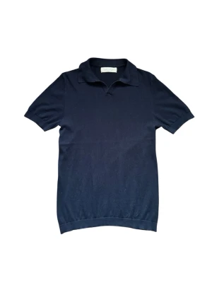 Sayless piké - Klassisk mörkblå pikétröja med krage och korta ärmar. Tröjan har en enkel och stilren design utan synliga loggor eller mönster, perfekt till jeans eller kjol. Mjuk och bekväm, passar till många olika looks.