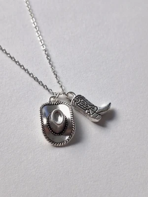Silverhalsband med cowboytema - Snyggt halsband i silverfärg rostfritt stål med två hängen – en cowboyhatt och en detaljrik cowboyboot. Kedjan är tunn och smidig, och båda hängen har cool westernstil. Retro style 🤠