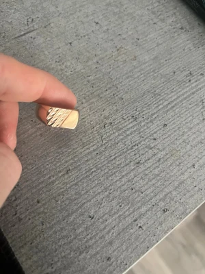 Guldplaterad ring med mönster - Snygg guldplaterad  ring med rektangulär platta och diagonala räfflade detaljer på ovansidan. Ringen har en modern och stilren design som sticker ut. Perfekt accessoar för att lyfta din outfit.