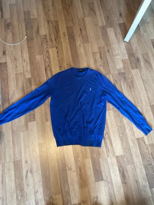 Blå tröja från Polo Ralph Lauren - Snygg blå tröja från Polo Ralph Lauren i slim fit-modell. Tröjan har rund halsringning, långa ärmar och den klassiska lilla logotypen broderad på bröstet. Perfekt för dig som gillar stilrena och tidlösa plagg. 