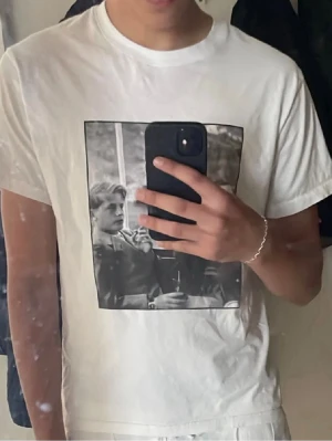 T-shirt med tryck  - Vit t-shirt från Flore med ett riktgt snyggt tryck på framsidan. Klassisk passform och rund halsringning. Perfekt för dig som gillar stilrena och roliga T-shirts en helt plain.