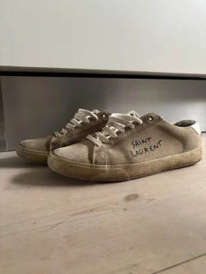 Beige Saint Laurent sneakers - Snygga beige sneakers från Saint Laurent med handskriven logga på sidan. Storleken står 41 men dom sitter som 43 
