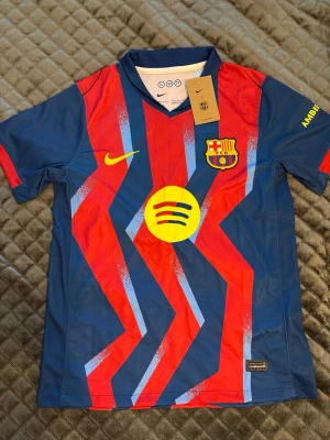 Barcelona matchtröja Nike blå/röd - Säljer en officiell FC Barcelona matchtröja från Nike i blått och rött med gula detaljer. Tröjan har klubbmärke, Nike-logga och Spotify-logga på bröstet samt Dri-FIT-material som andas. Snygg V-ringning och coolt mönster framtill.