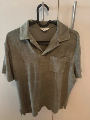Grön frotté polotopp - Snygg grön polotopp från East West i mjuk frotté. Toppen har korta ärmar, klassisk krage och en bröstficka. Perfekt för en avslappnad och trendig look.