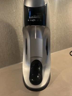 SodaStream kolsyremaskin silver - Säljer en SodaStream kolsyremaskin i silver och svart. Maskinen har en modern design och är tillverkad i plast och metall. Perfekt för att göra eget bubbelvatten hemma. Enkel att använda och passar snyggt på köksbänken.